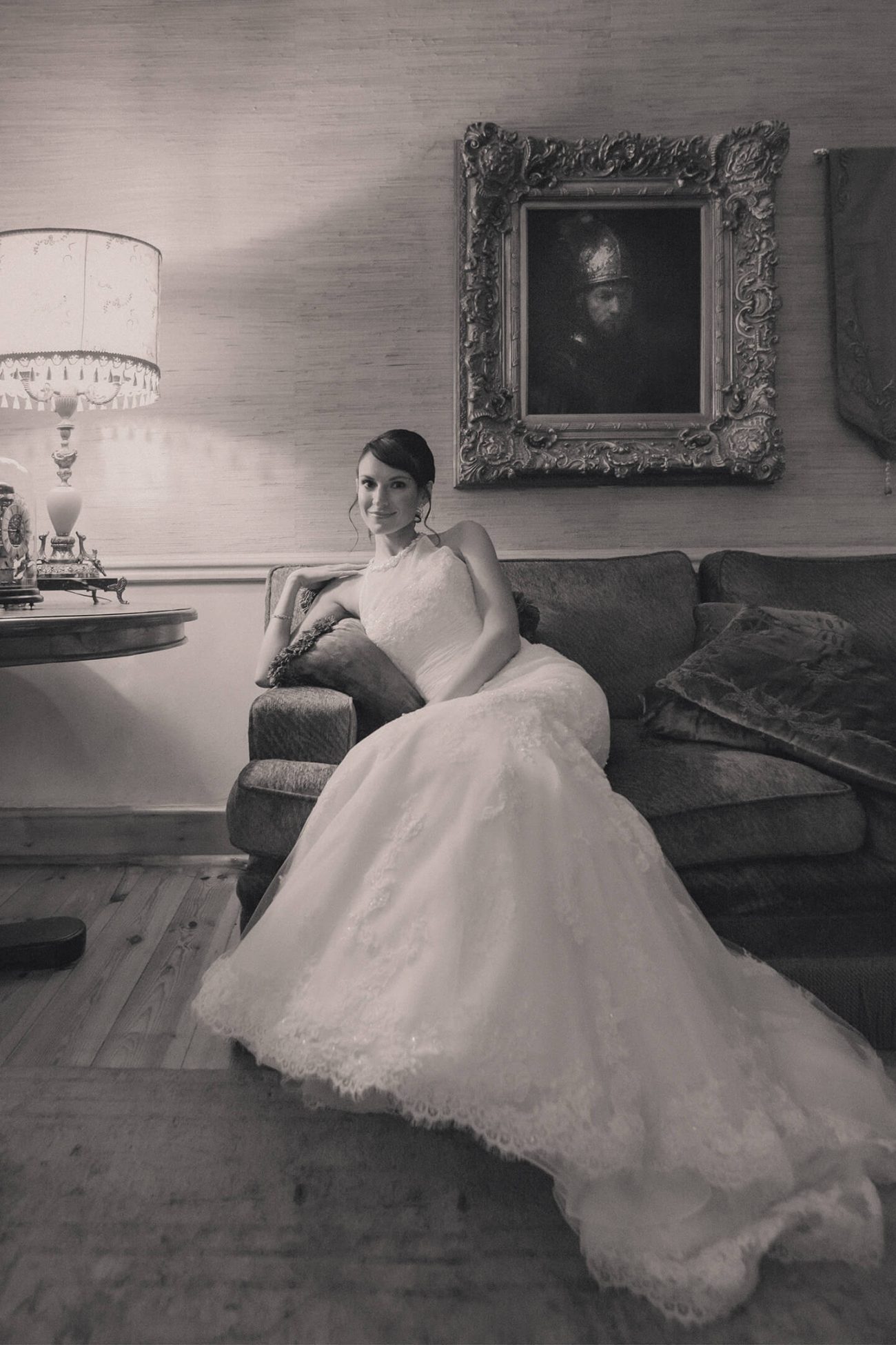 Black and white portrait of a bride reclining on a vintage couch at Le Manoir in Northcliff, Johannesburg, capturing the classic European ambiance of the venue.