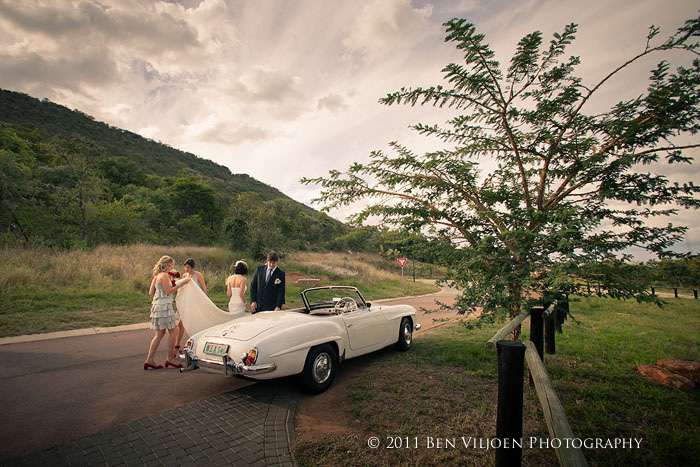 Bride stepping out of a classic Mercedes-Benz 190SL, surrounded by her bridesmaids at Euphoria Golf Estate, Limpopo.