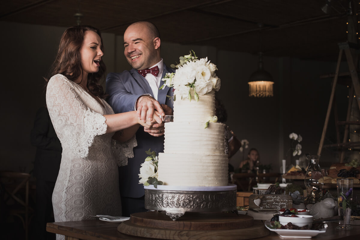 Bride and groom enjoying a fun moment while cutting their wedding cake