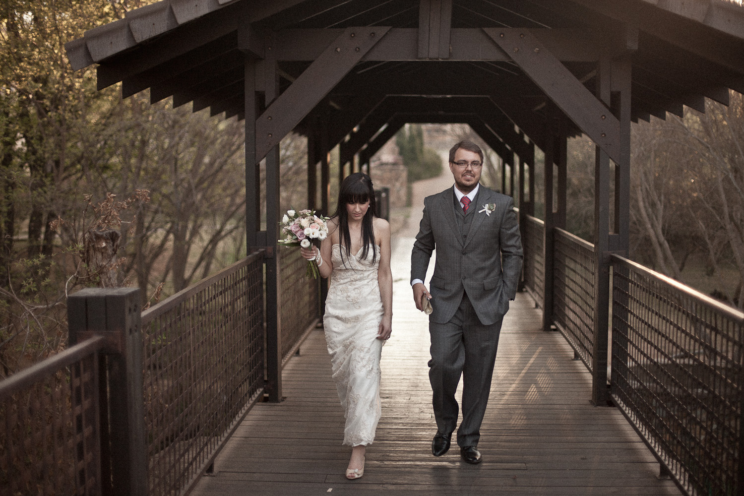 Bridal couple walking across a stone bridge towards the camera at Avianto, a popular wedding venue in Muldersdrift.