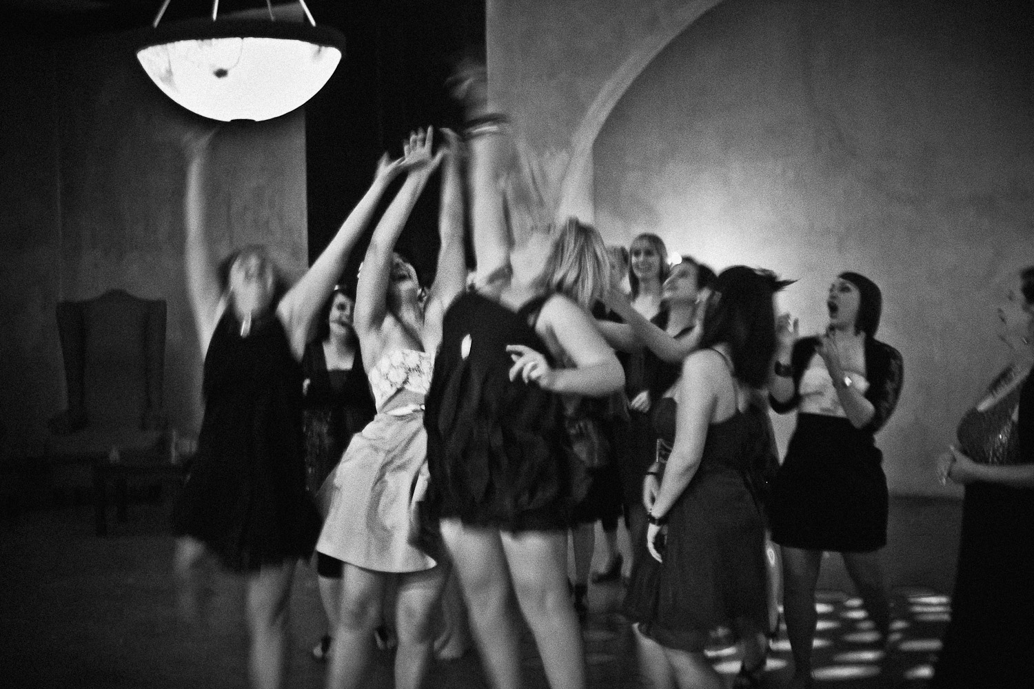 Black and white image of single ladies eagerly reaching for the garter during the wedding reception at Avianto, capturing a lively and fun moment.